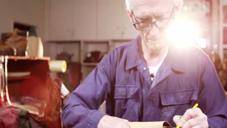 shoemaker marking a piece of leather on shoe last