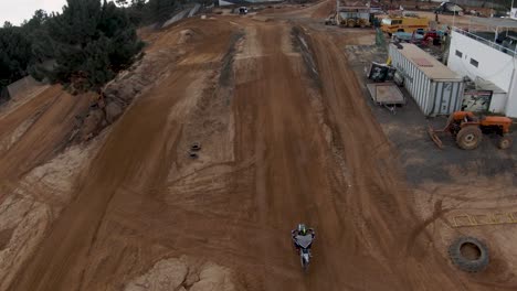 FPV-Dolly-Aus-Der-Luft-Vorwärts,-Während-Der-Motocross-Dirtbike-Fahrer-Unten-Einsteigt