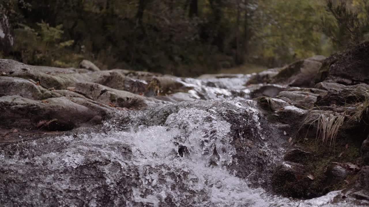 Jib-slowmotion-optagelse af flodstrømfald med vand, der sprøjter på klipperne