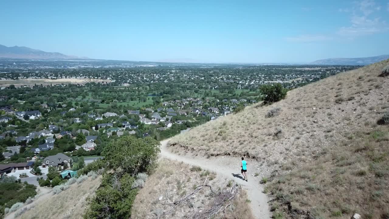 disparo de un dron siguiendo a un hombre activo corriendo por los senderos de montaña al aire libre sobre draper city, utah