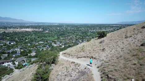 drone shot following an active man running on the outdoor mountain trails above draper city, utah