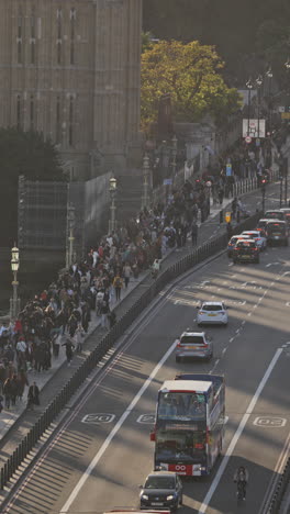 el tráfico y la gente que cruza el puente de westminster al lado de las casas del parlamento, londres, reino unido en vertical