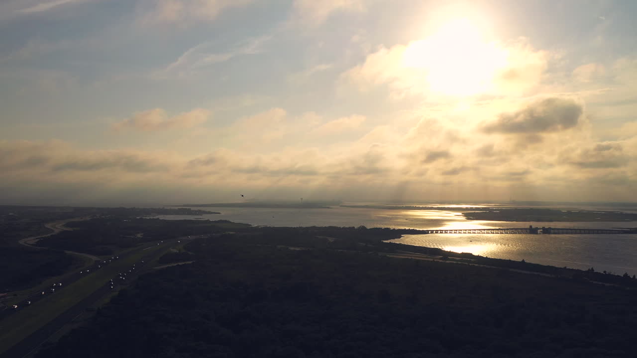vista aérea sobre el pantano - camino frente a la puesta de sol dorada mientras un pájaro investiga el dron en vuelo