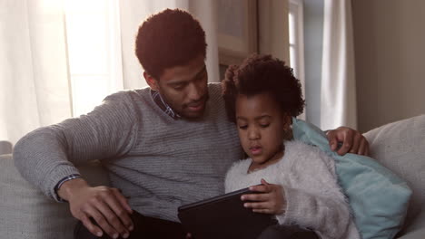 Father-And-Daughter-On-Sofa-With-Digital-Tablet-Shot-On-R3D