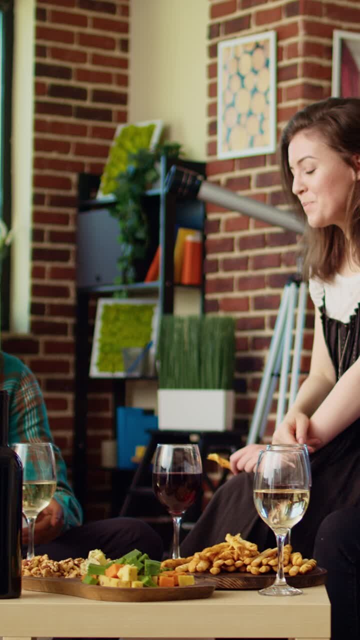 Vertikal video: Forskellige venner har det sjovt sammen og skåler med vin- og champagneglas i en lejlighed for at fejre noget