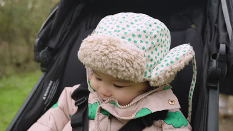 adorable asian baby laughs in stroller whilst wearing warm wooly hat to keep him warm during winter