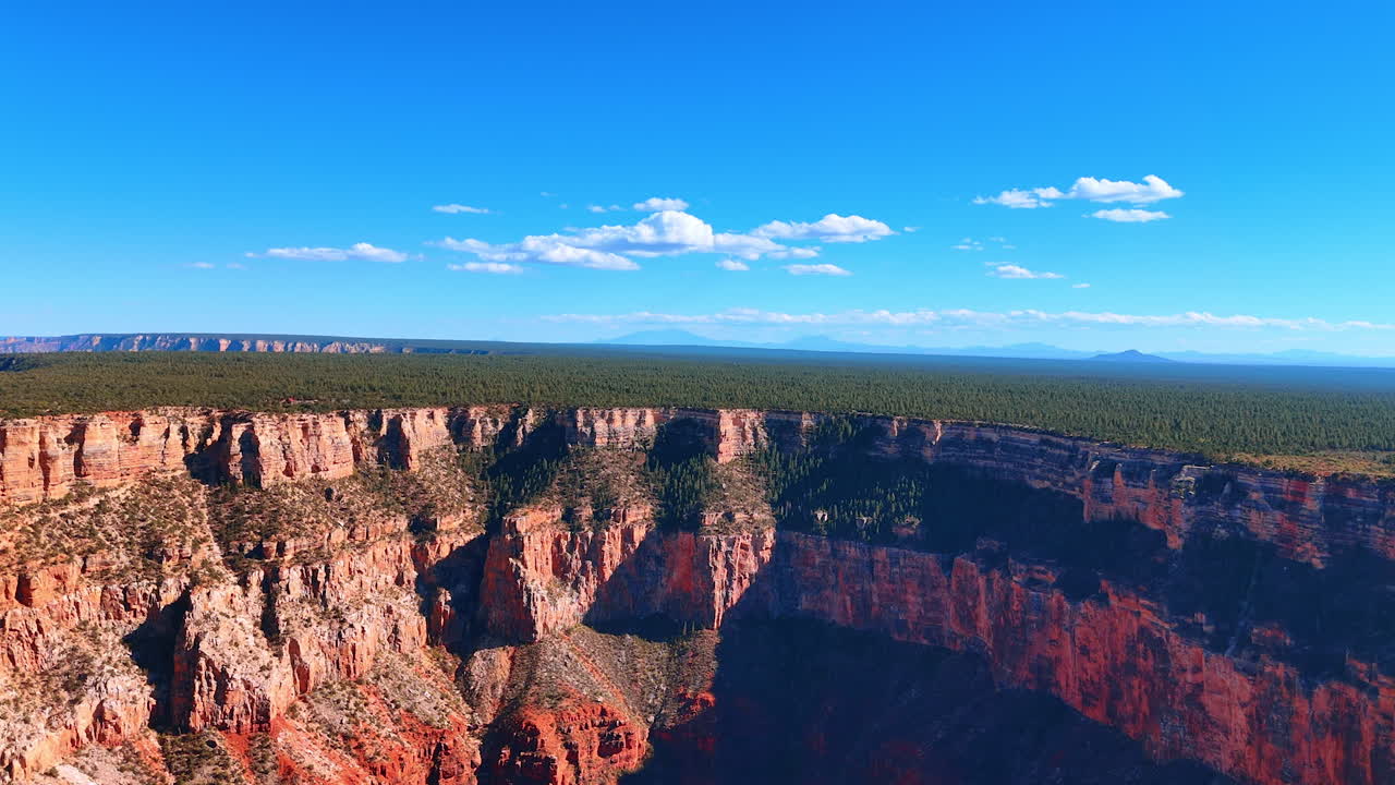 Grand Canyon cliffs under clear blue sky. A wide aerial view of the Grand Canyon showing rugged red cliffs under a bright blue sky