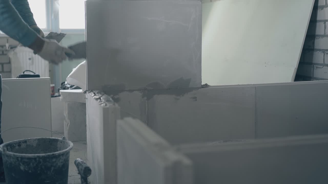 skilled repair worker holds big putty knife and smears wall