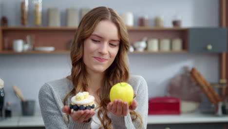 Closeup-thoughtful-woman-looking-at-creamy-dessert-and-fresh-apple-in-kitchen