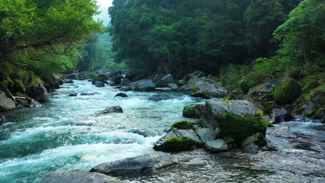 Low-aerial-over-strong-flowing-Kirishima-River-with-clear-water-through-lush-landscape---Japan-natural-beauty