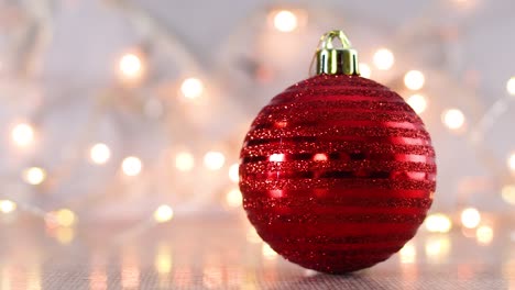 red shiny ornament with blinking christmas lights behind