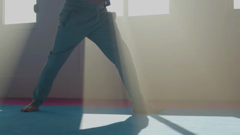 Man-slowly-bending-toward-legs-while-practicing-tai-chi-in-gym