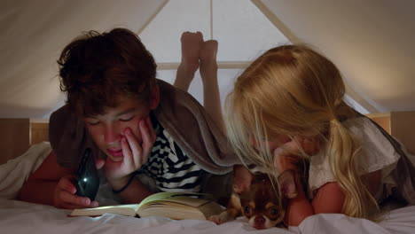 children reading a book together at night with their pet chihuahua