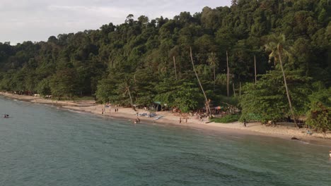 Tropeninsel-Drohne,-Trucking,-Aufnahme-Mit-Regenwald-Und-Palmen-Mit-Weißem-Sandstrand,-Kajaks,-Kleine-Strandbars-Mit-Einigen-Thailändischen-Inlandstouristen,-Die-Ein-Langes-Wochenende-Genießen