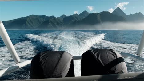 speed boat with two hug outboard engines while underway with spectacular tahiti mountains on the horizon