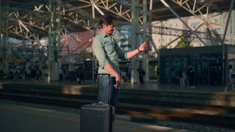 handsome solo male traveler checking phone at seoul train station, south korea, stylish and urban setting as he raises phone to take selfie and make peace sign