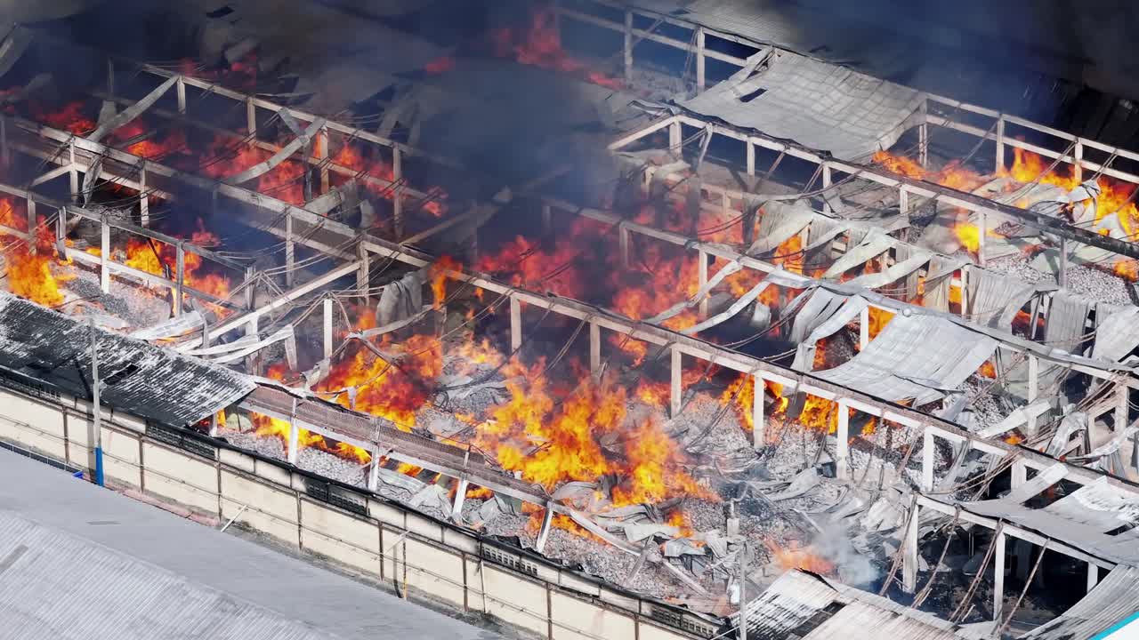 Devastated warehouse burning with big flames, aerial observation, fire accident
