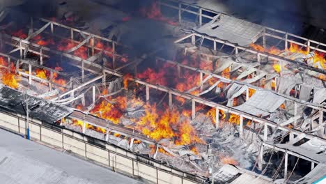 devastated warehouse burning with big flames, aerial observation, fire accident