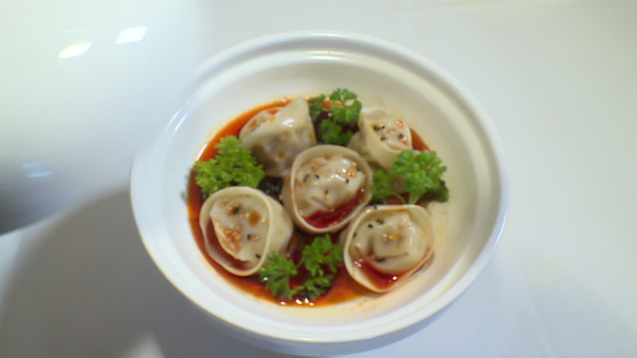 Closing the lid of a white bowl and a dish of dumplings in a white bowl
