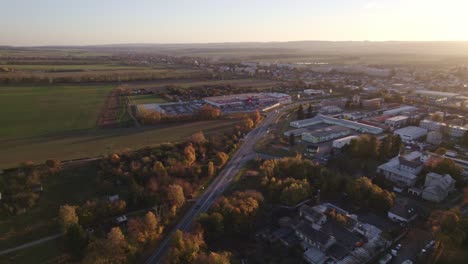 ariel-aufnahme einer wunderschönen autobahn bei sonnenuntergang, umgeben von bäumen und häusern auf der rechten straßenseite und grüner vegetation auf der linken straßenseite