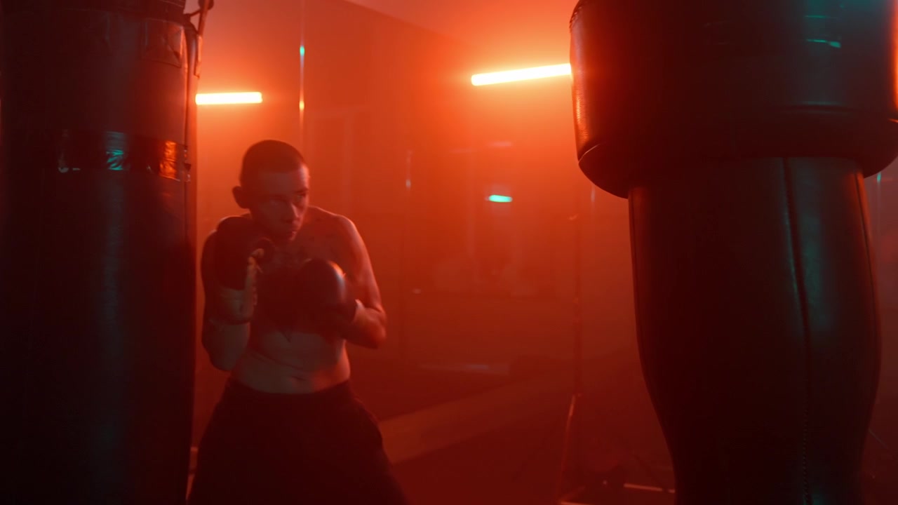 Pugile a torso nudo si allena con un sacco da boxe in una palestra illuminata al neon con luci suggestive
