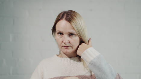 vrouw van middelbare leeftijd die naar haar haar in de spiegel kijkt