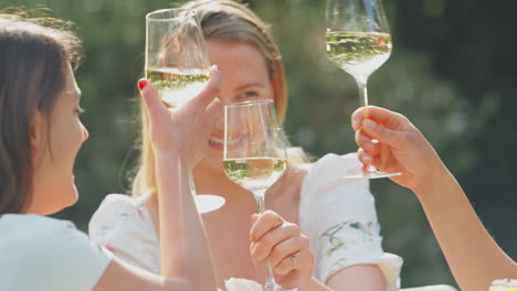 Drei-Freundinnen-Sitzen-Draußen-Im-Sommergarten-Zu-Hause,-Trinken-Wein-Und-Stoßen-An