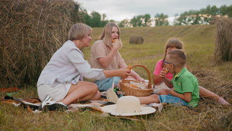 peaceful family seated on grass enjoying fresh pastries from picnic basket, they pick egg rolls and other baked goods while sharing a meal together in a serene countryside setting