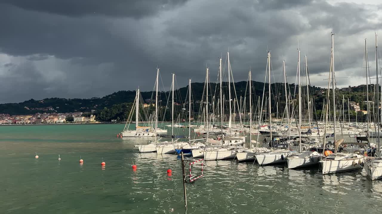 Lerici Marina boats facing storm clouds with San Terenzo’s colorful seaside town in the distance
