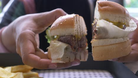 hands holding a half-eaten cheeseburger