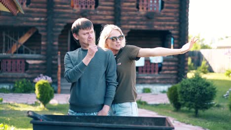 Travelling-Young-guy-with-girl-standing-near-the-barbecue-in-which-coals-are-smoking