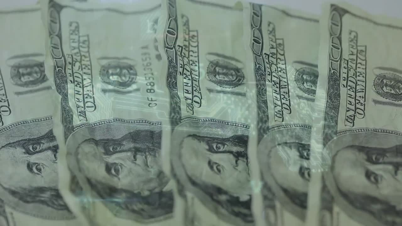 animación de números y letras cambiantes sobre billetes de dólar apilados a mano