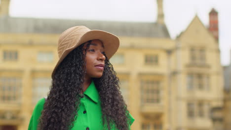 female tourist wearing straw sun hat with camera on vacation in oxford uk exploring city walking along broad street taking photos of the sheldonian theatre 2