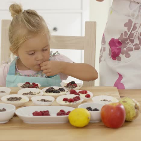 Süßes-Kleines-Mädchen,-Das-Beeren-Auf-Muffins-Setzt