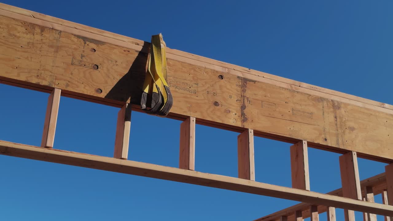 Slow horizontal pan of exposed beam and rigging strap against clear blue sky