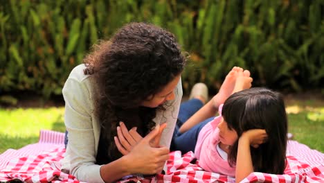 madre e hija acostadas charlando en el césped