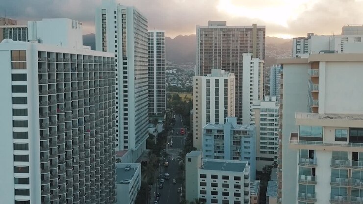 Drone aéreo panorâmico voando lentamente sobre o colorido horizonte de Honolulu durante o pôr do sol em Oahu, Havaí, com a Praia de Waikiki como um ponto de interesse especial
