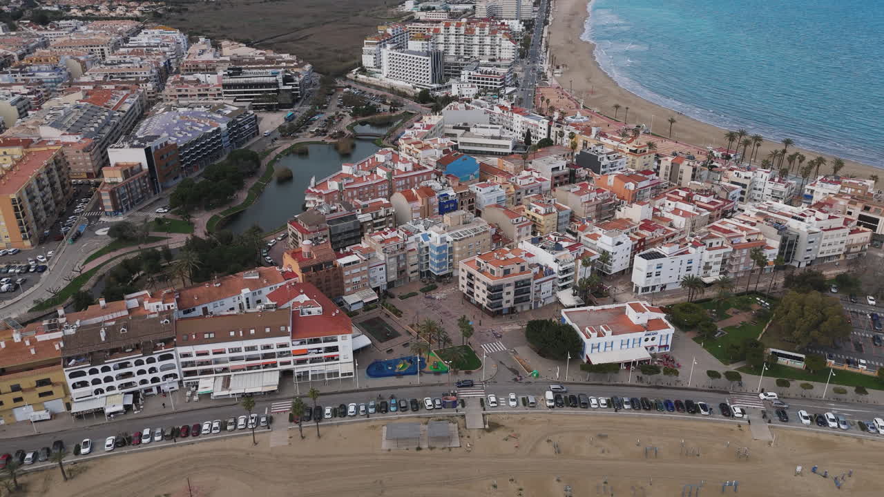 Drone glides along coast of Peniscola showing town rooftops and castle above sea
