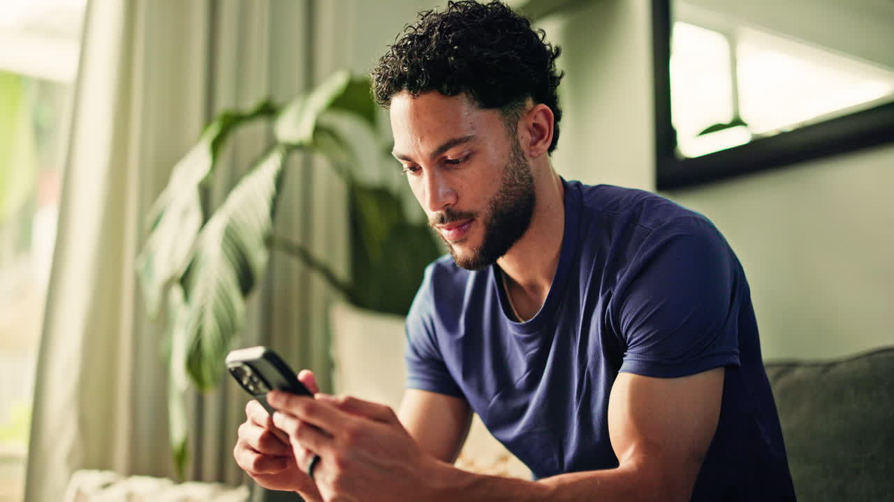 Giovane uomo che scorre il telefono cellulare a casa