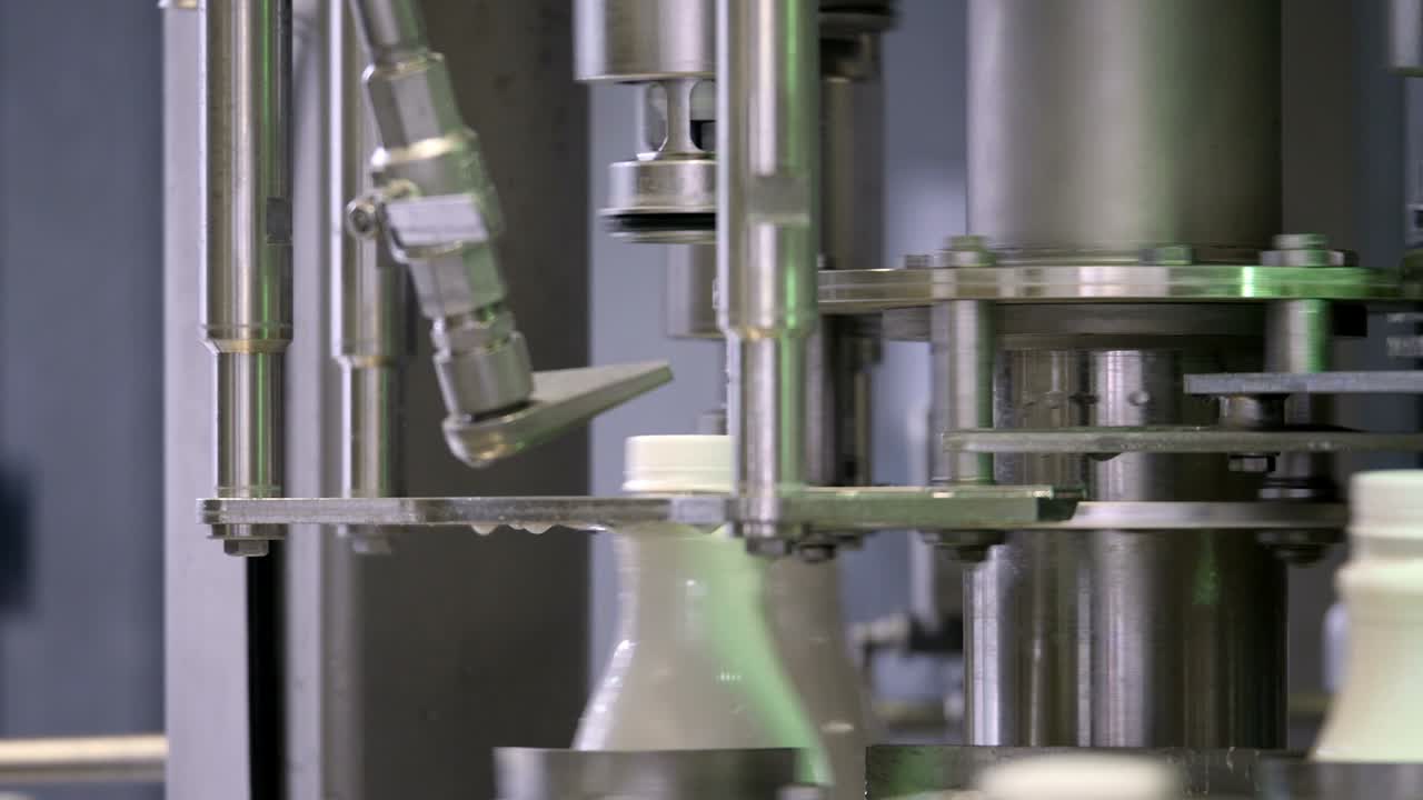 우유 회사에서 생산 라인에서 색 플라스틱 우유 병의 영상, 병이 채워지고 봉인됩니다.