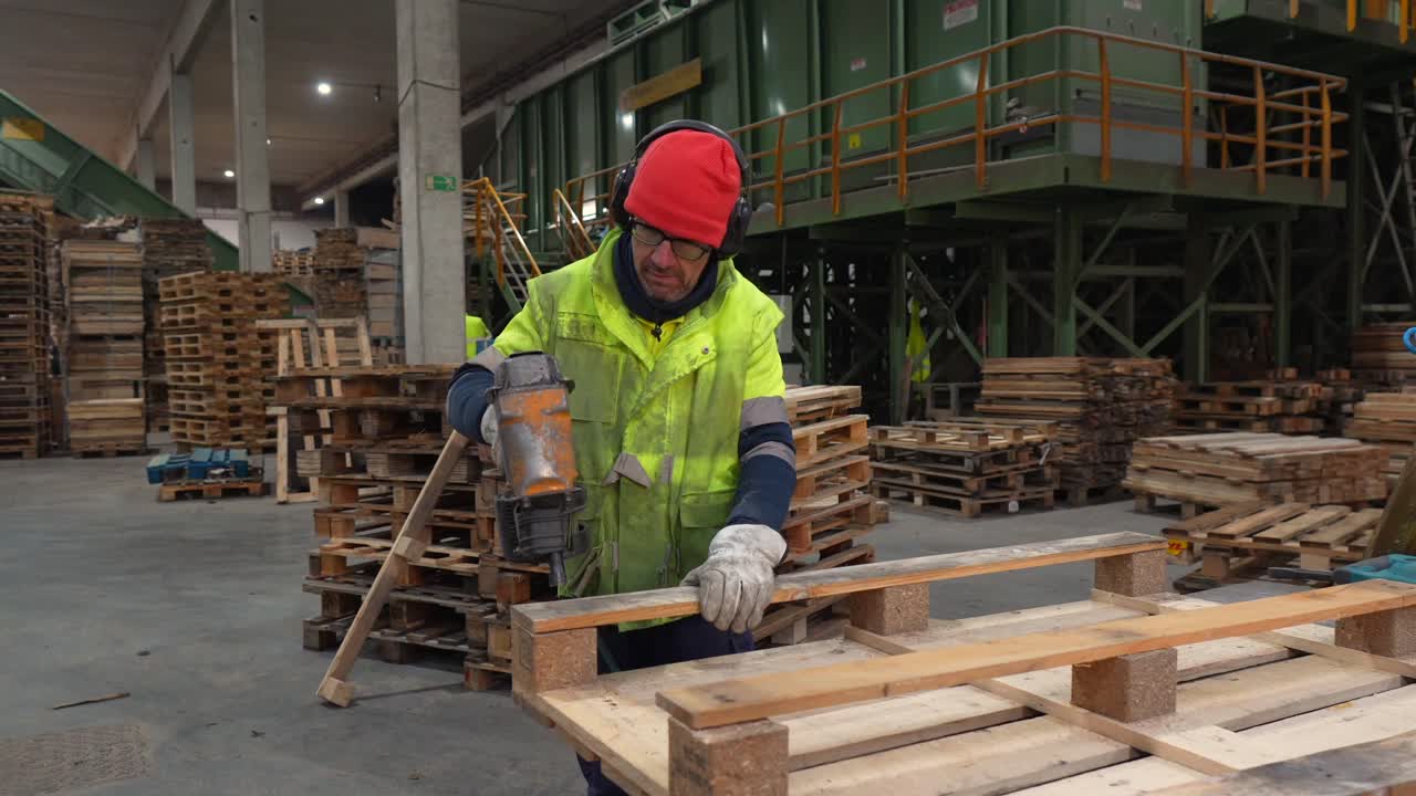 Worker Assembling Pallets with Nail Gun in Factory