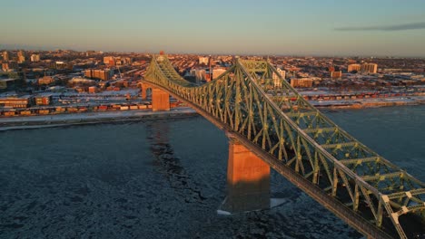 an elevated aerial view of montreal’s steel bridge spanning across the frozen st. lawrence river, north america, quebec, montreal, canada.