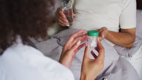 Senior-mixed-race-man-with-female-doctor-home-visiting-and-taking-pills