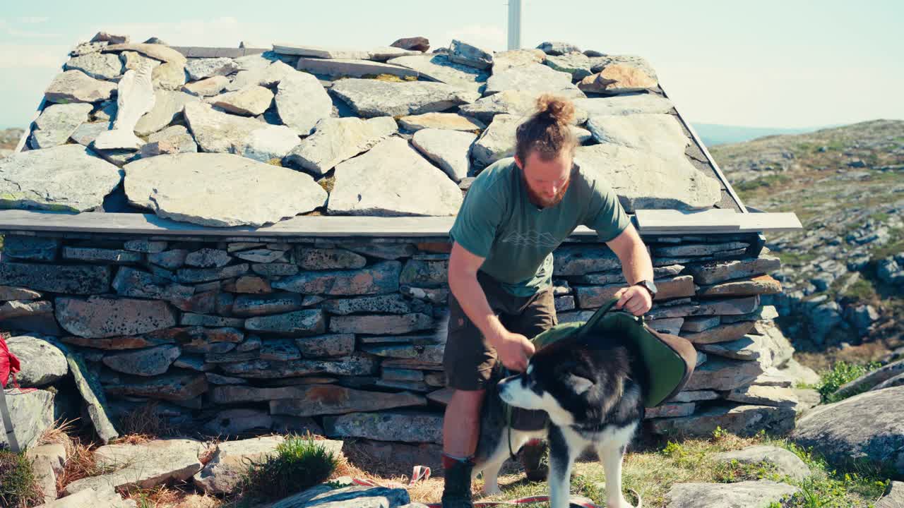 Male Hiker And Alaskan Malamute Dog Preparing For Hiking - Wide Shot