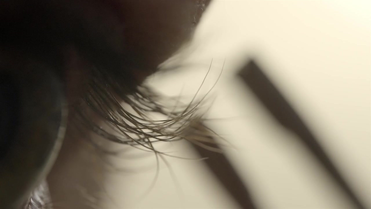 Macro shot of a person using tweezers for precise eyelash removal
