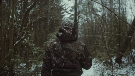 vista trasera de un cazador caminando en la nieve con un rifle y camuflado durante el viaje de caza, caza de invierno