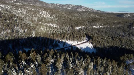 Aerial-drone-shot-of-a-car-going-down-a-winding-road-in-the-mountains