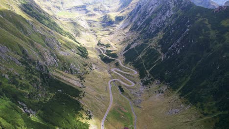 Vista-Panorámica-Aérea-De-La-Serpenteante-Carretera-Transfagarasan-Mientras-Las-Nubes-Pasan-Sombras-Sobre-El-Paisaje-Herboso