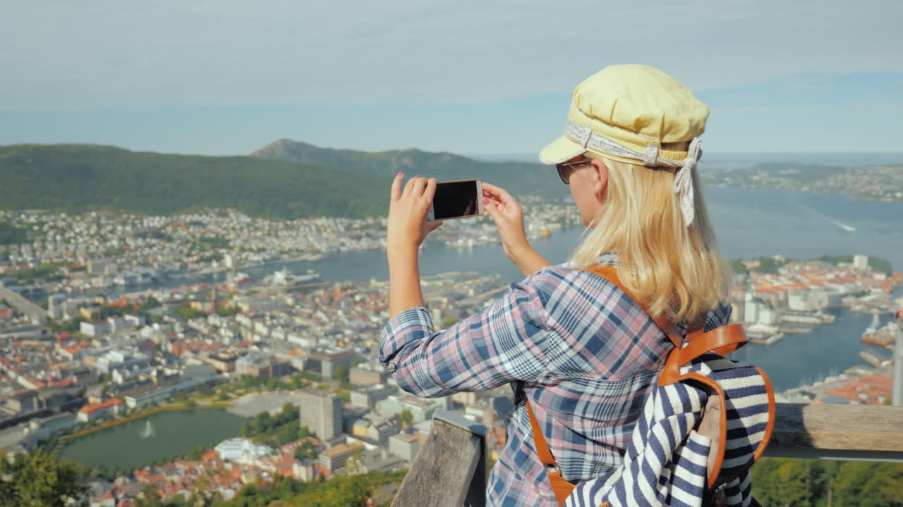 mujer joven toma una foto de la ciudad de bergen se encuentra en la plataforma de observación turismo en escaneo