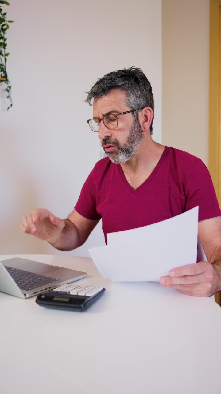 Hombre estresado calculando finanzas y revisando documentos en casa